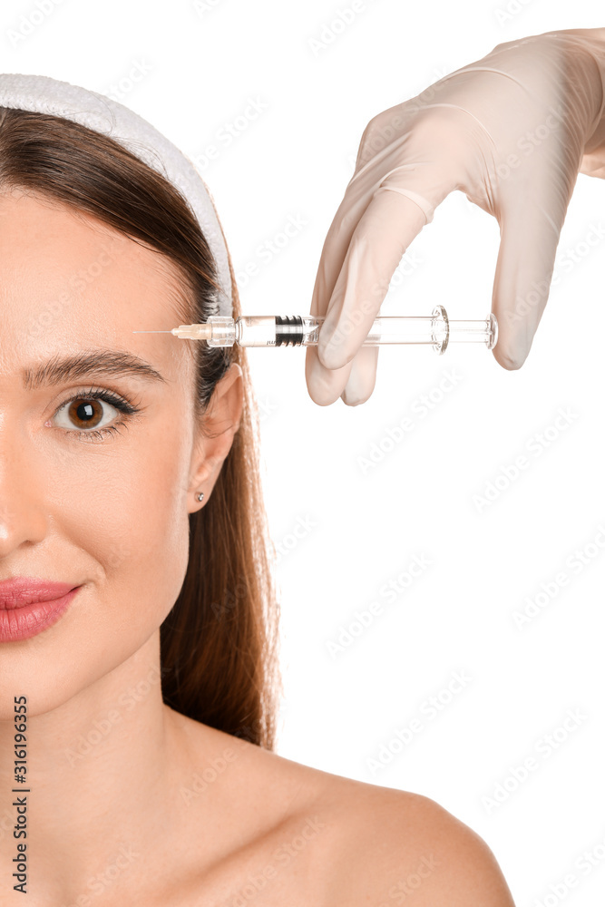 Fototapeta premium Young woman receiving filler injection against white background