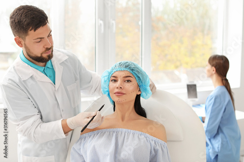Plastic surgeon applying ma...