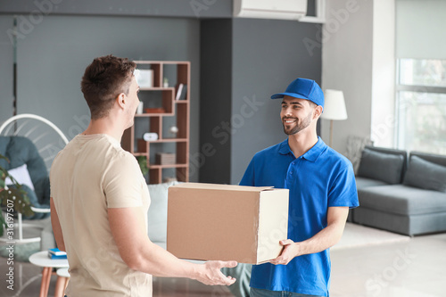 Man receiving parcel from courier of delivery service at home