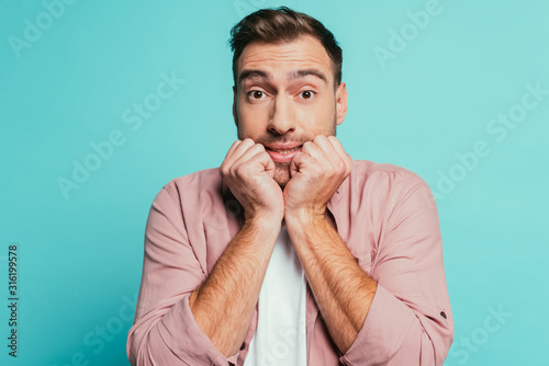 frightened handsome man gesturing isolated on blue