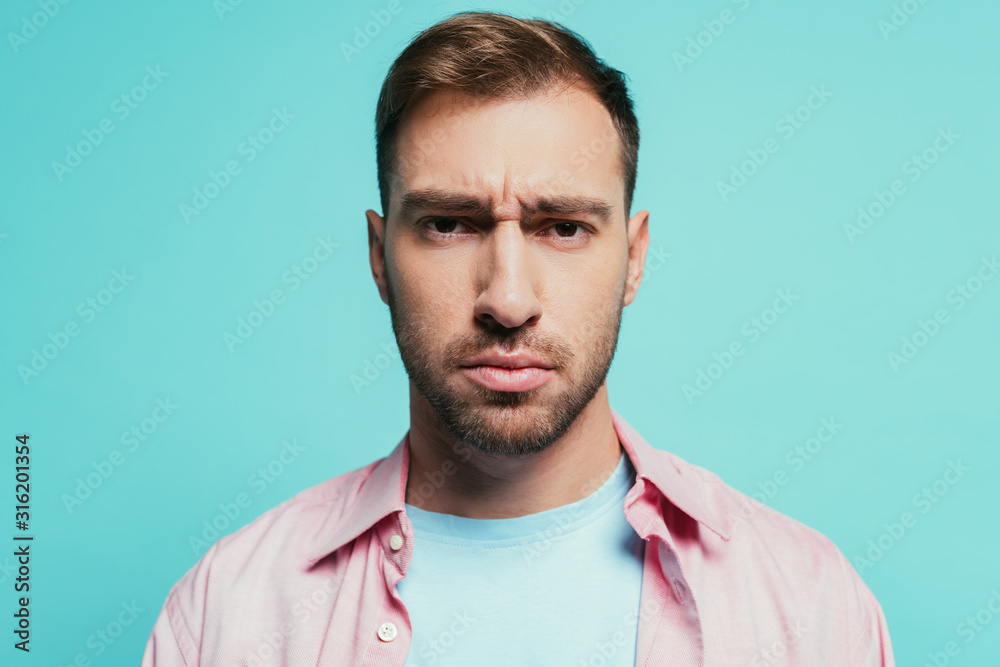 Obraz premium portrait of serious handsome man looking at camera, isolated on blue