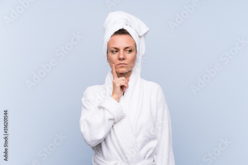 Woman in bathrobe over isolated blue background thinking an idea