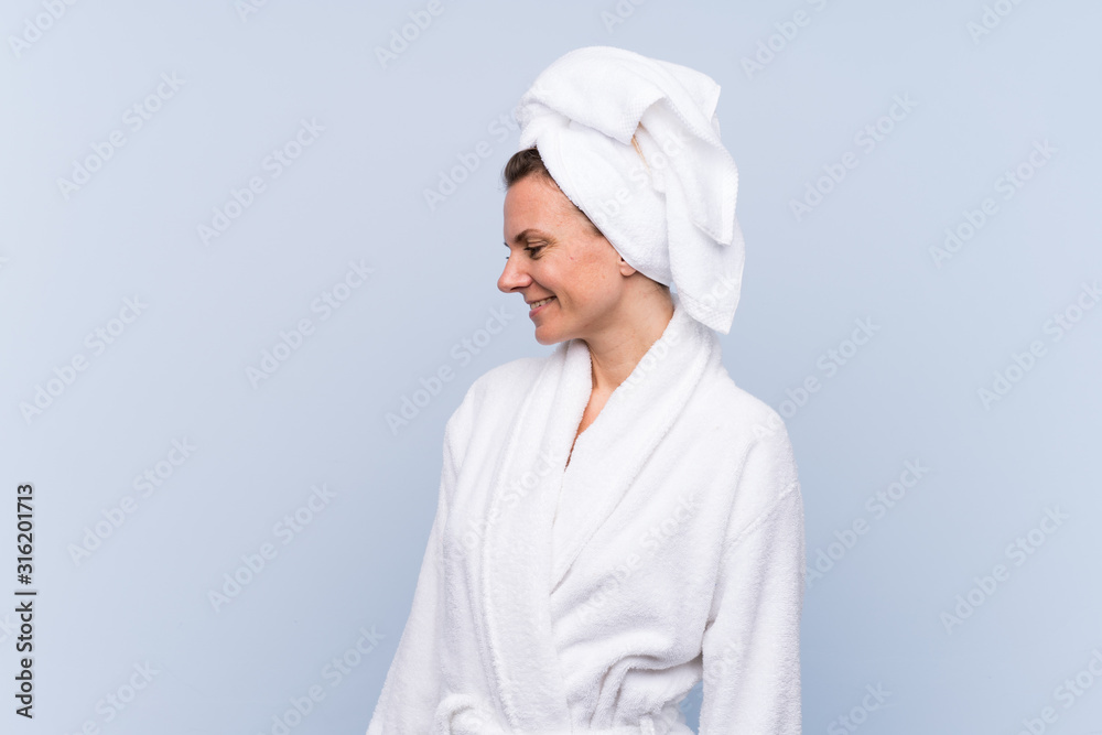 Woman in bathrobe over isolated blue background looking to the side
