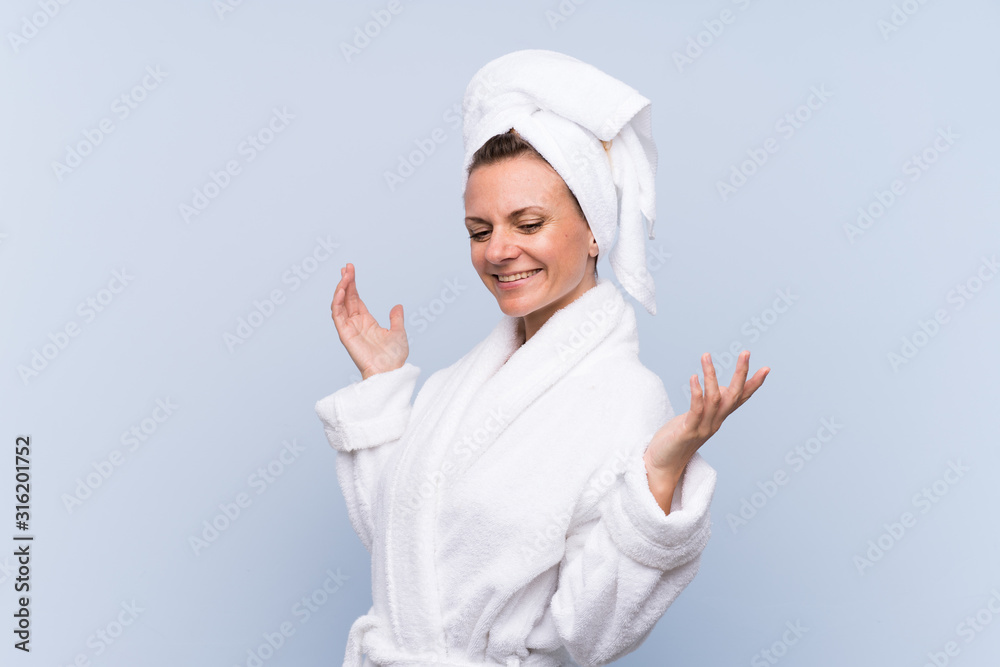 Woman in bathrobe over isolated blue background laughing Woman in bathrobe over isolated blue background laughing