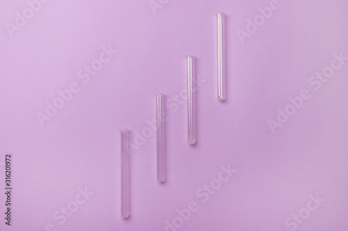 four test tube lying on diagonal on purple colored background