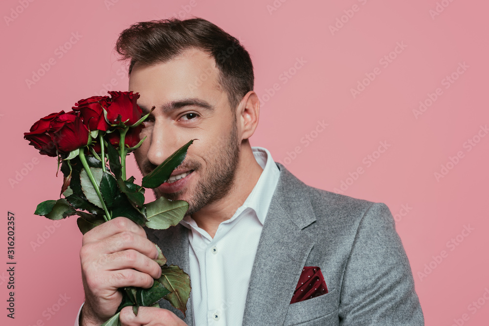 cheerful man in suit holding red roses, isolated on pink cheerful man in suit holding red roses, isolated on pink