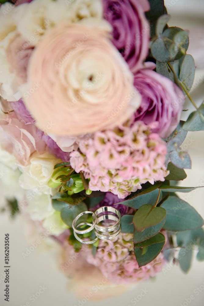 Close up of two golden wedding rings and bridal bouquet on mirror table, copy space. Selective focuse. Wedding concept