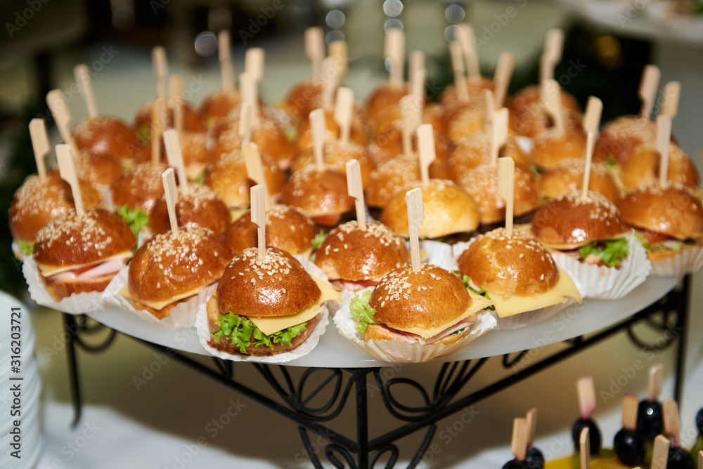 Buffet table with mini hamburgers at luxury wedding reception, copy space. Serving food and appetizers at restaurant. Catering banquet table Buffet table with mini hamburgers at luxury wedding reception, copy space. Serving food and appetizers at restaurant. Catering banquet table