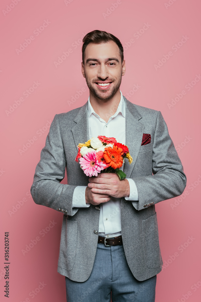 smiling man holding bouquet of flowers, isolated on pink smiling man holding bouquet of flowers, isolated on pink
