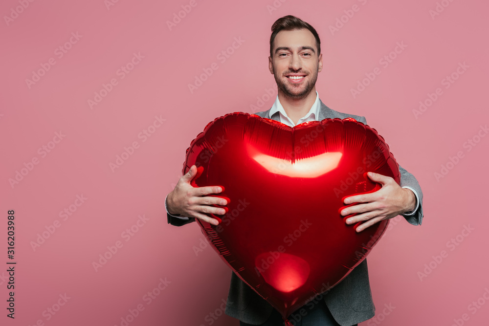 happy bearded man holding red heart balloon on valentines day, isolated on pink happy bearded man holding red heart balloon on valentines day, isolated on pink