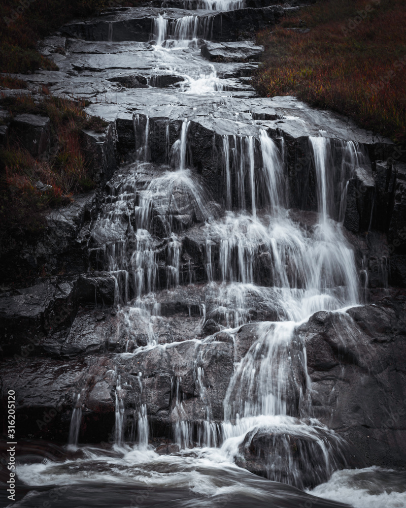 Fototapeta premium Waterfall in Scottish Highlands.Cascade of water splashing on dark rocks in Etive valley, Glencoe,Scotland, UK.Power in nature.Motion of flowing water.Tranquil landscape scene.Horizontal nature image.