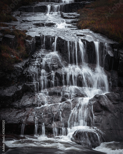 Waterfall in Scottish Highlands.Cascade of water splashing on dark rocks in Etive valley  Glencoe Scotland  UK.Power in nature.Motion of flowing water.Tranquil landscape scene.Horizontal nature image.