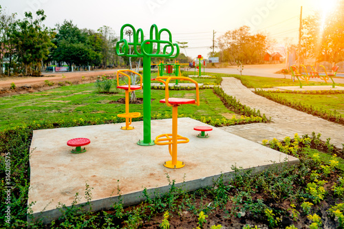 Plubic gym exercise concept, exercise machine outdoor in park for people playing to good healthy, grass meadow and flower around machine, playgrond for kid and person to play fitness outdoor lifestyle photo