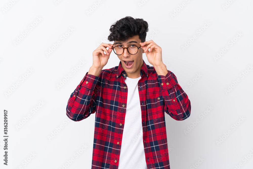 Young Argentinian man over isolated white background with glasses and surprised Young Argentinian man over isolated white background with glasses and surprised