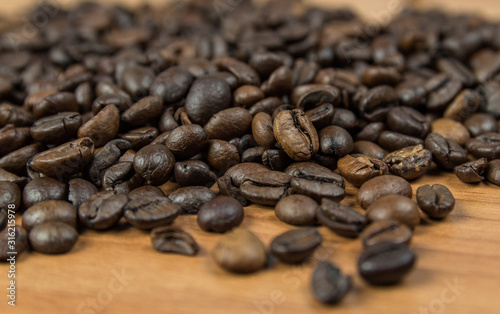 close up view of piled up roasted coffee beans on a wooden surface