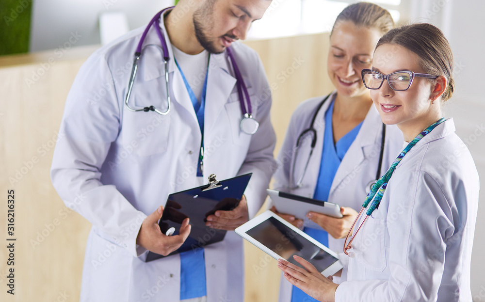 Doctor showing something in his tablet to his medical team Doctor showing something in his tablet to his medical team
