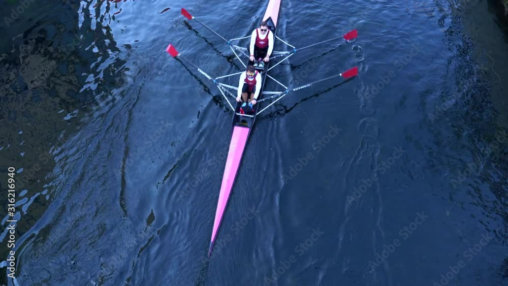 Rowboat with unrecognizable rowers seen from above.