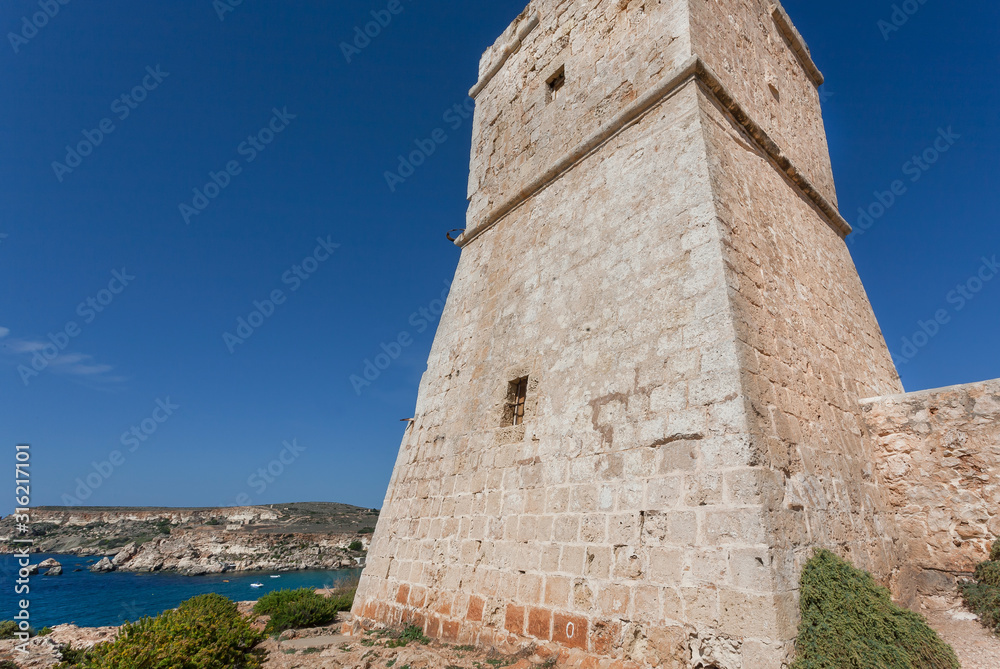 Lighthouse on a hill over Mediterranian sea. Scene view of sunny coastline in Malta Lighthouse on a hill over Mediterranian sea. Scene view of sunny coastline in Malta