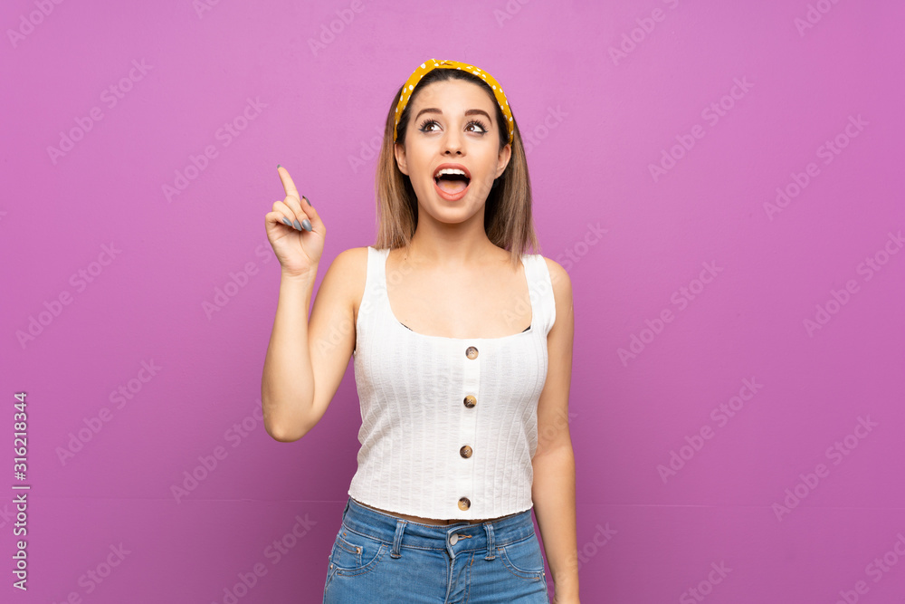 Pretty young woman over isolated purple wall intending to realizes the solution while lifting a finger up Pretty young woman over isolated purple wall intending to realizes the solution while lifting a finger up
