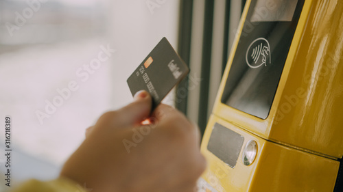 Girl paying conctactless with bank card for the public transport in the tram