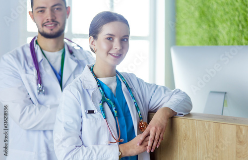 Young doctors are standing inside the hospital and looking at camera photo