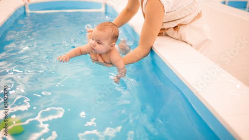 Litle baby in pool swimming bathing during health procedures.