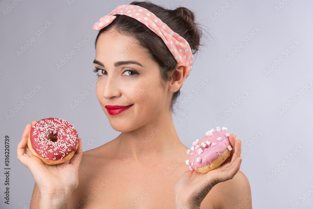 bellissima ragazza anni 50 tiene in mano dei donuts - isolata su sfondo rosa bellissima ragazza anni 50 tiene in mano dei donuts - isolata su sfondo rosa