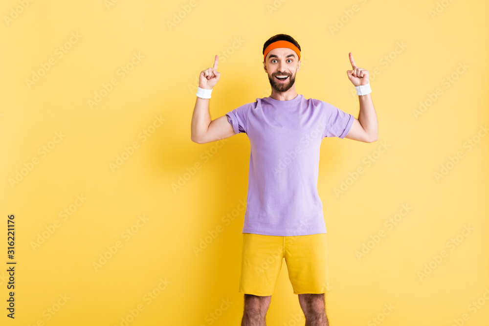 happy man in headband pointing with fingers on yellow happy man in headband pointing with fingers on yellow