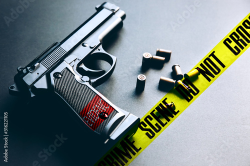 Gun with bullets lying on the table. Legalising of weapons. Crime scene do not cross tape. photo