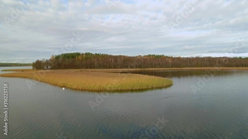Low aerial flight above lake during fall, Suwalszczyzna, Poland, towards shot