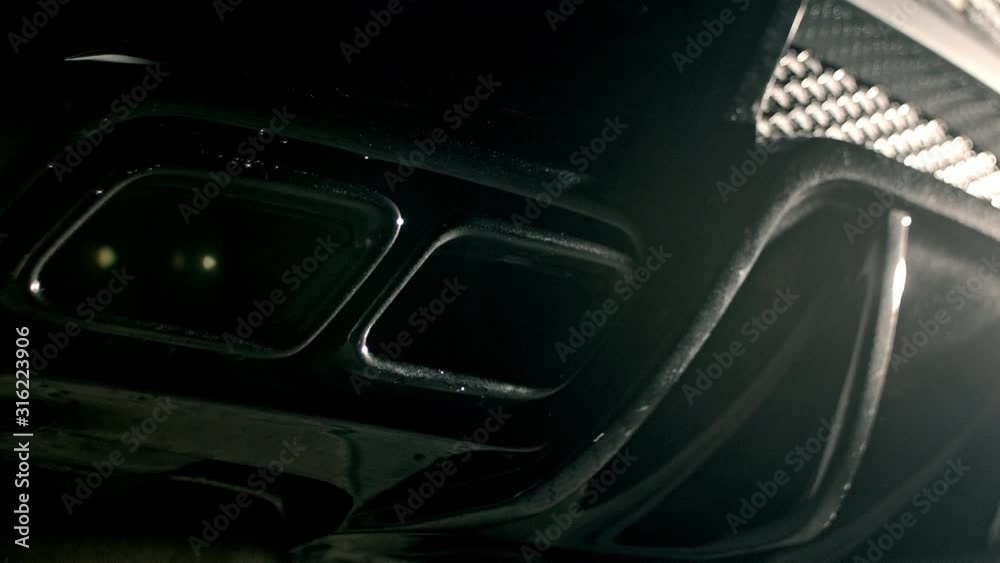 Car exhaust pipes spitting water during engine startup in slow motion, high quality prores