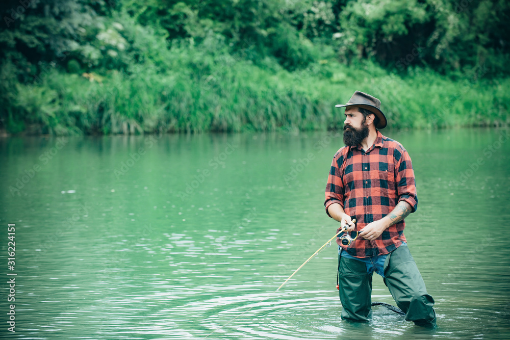 Man with fishing rods on river berth. A fisherman with fishing rod on the river. Man fishing and relaxing while enjoying hobby. Fly fishing is most renowned as a method for catching trout and salmon. Man with fishing rods on river berth. A fisherman with fishing rod on the river. Man fishing and relaxing while enjoying hobby. Fly fishing is most renowned as a method for catching trout and salmon.