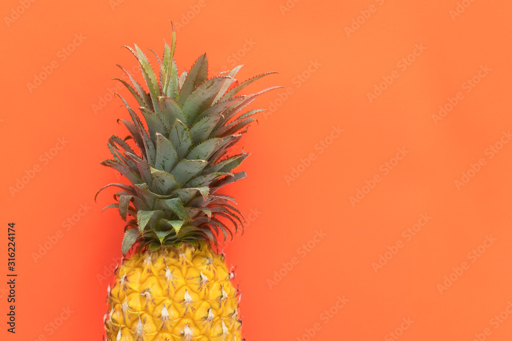 Fresh ripe pinapple, exotic tropecal yellow fruit, ananas on orange background with copy space, place for text. Vacation, summer or healthy food, diet concept.