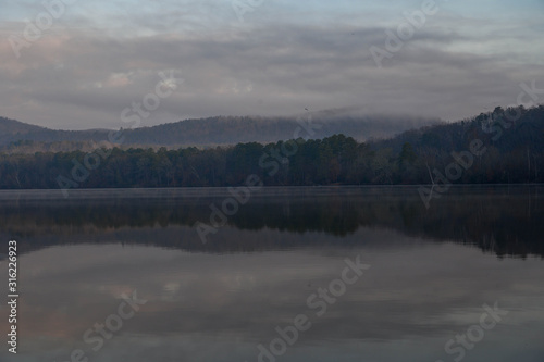 The reflections of the rolling mountains on a cloudy early morning. The haze over the water on a cold winter sunrise morning.