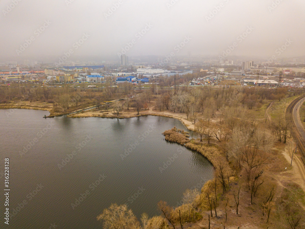 Aerial drone view. Lake in the city on a foggy morning.