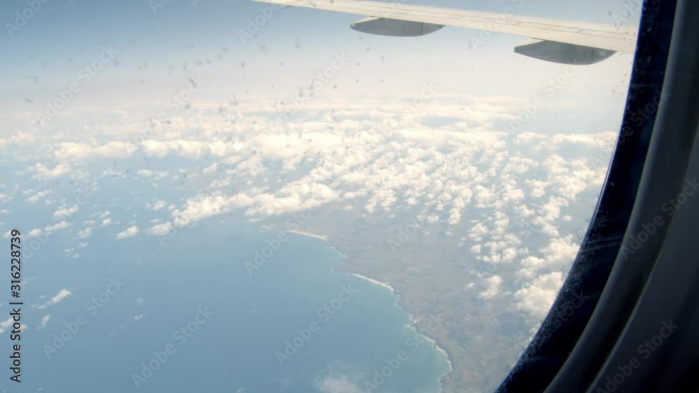 View outside airplane window of the coast and clouds