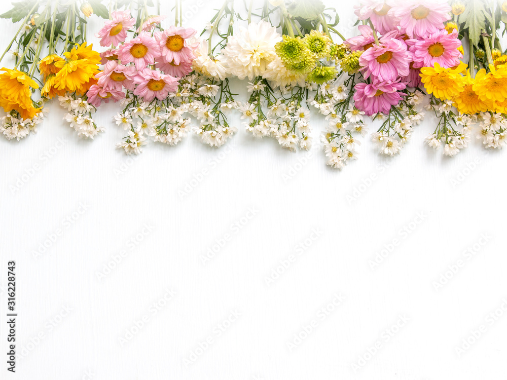 Many colorful flowers border on above of white wooden background. Top view. Love concept. Copy space.