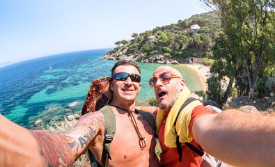 Best friends taking selfie at Giglio Island on adventure travel - Wanderlust lifestyle concept with gay couple enjoying happy fun moment - Trip together around world beauties - Bright vivid filter