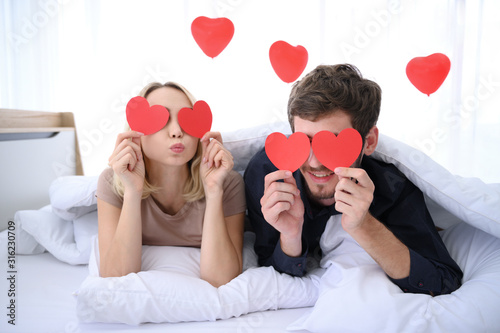 Couple. Love. Valentine's day. Man and woman are holding red paper hearts close their eyes with noughty face