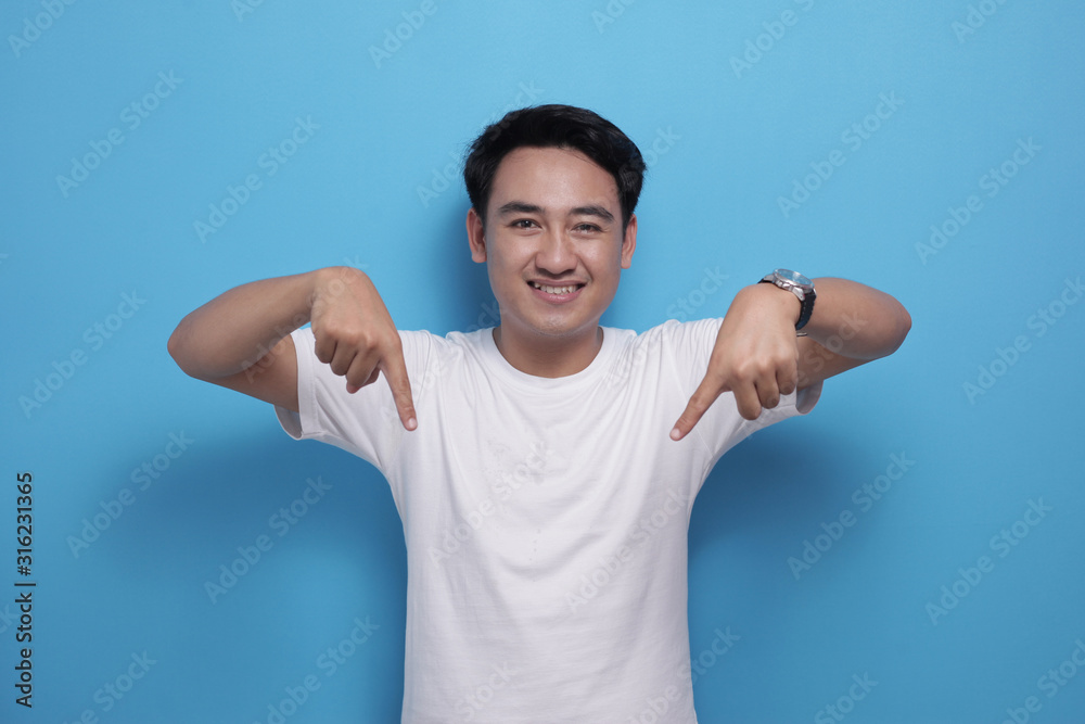 Young man smiling and pointing down, presenting something