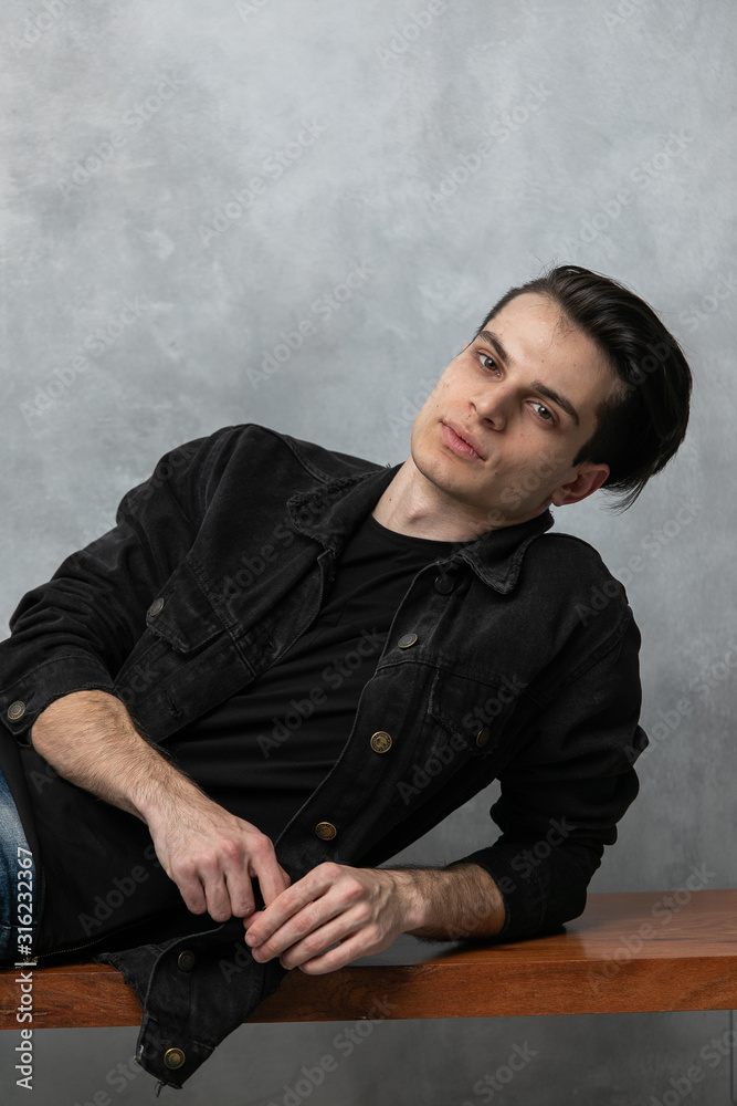 Φωτογραφία Studio fashion portrait of attractive young man in black jacket and blue jeans