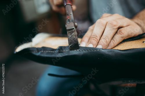 Close up shot of old shoemaker in his store. Traditional way of shoe making process.