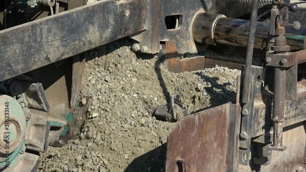 Road machinery that crushes stones and sets it on a country road Road machinery that crushes stones and sets it on a country road