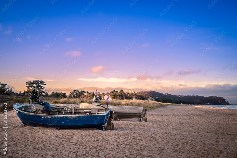 Fototapeta premium 2 Fischerboote am Strand mit Steilküste im Hintergrund vor beginnendem Abendrot