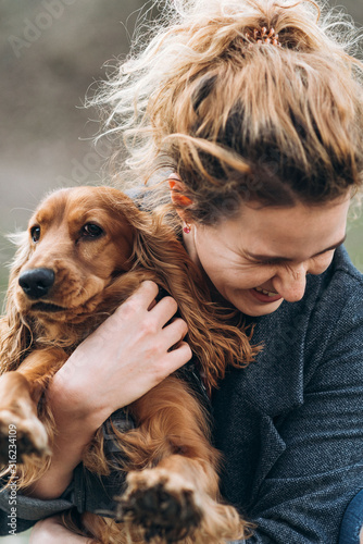 Attractive happy young curly woman hugs her favorite cocker spaniel dog