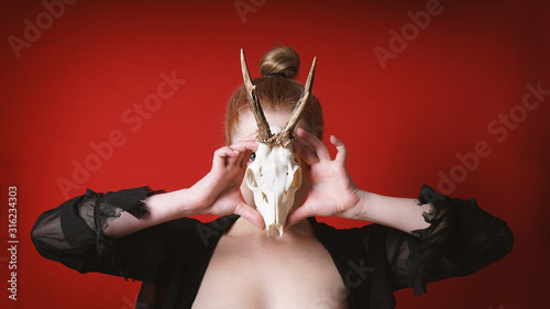 Stampa su tela mysterious occult woman holding animal deer skull in front of her face - animali