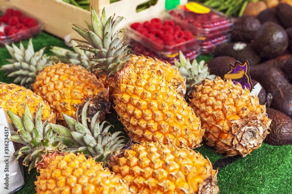 Different kinds of tropical fruits at market. Pineapple, avocado, raspberry. Fresh raw organic bio uncooked fruits for sale at farmers market. stock photo of fruits vegan food, healthy nutrition. Different kinds of tropical fruits at market. Pineapple, avocado, raspberry. Fresh raw organic bio uncooked fruits for sale at farmers market. stock photo of fruits vegan food, healthy nutrition.