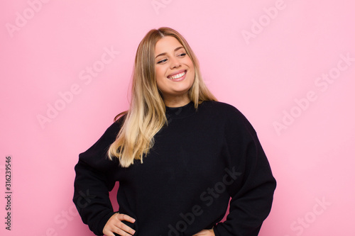 Konstfotografi young blonde woman looking happy, cheerful and confident, smiling proudly and lo