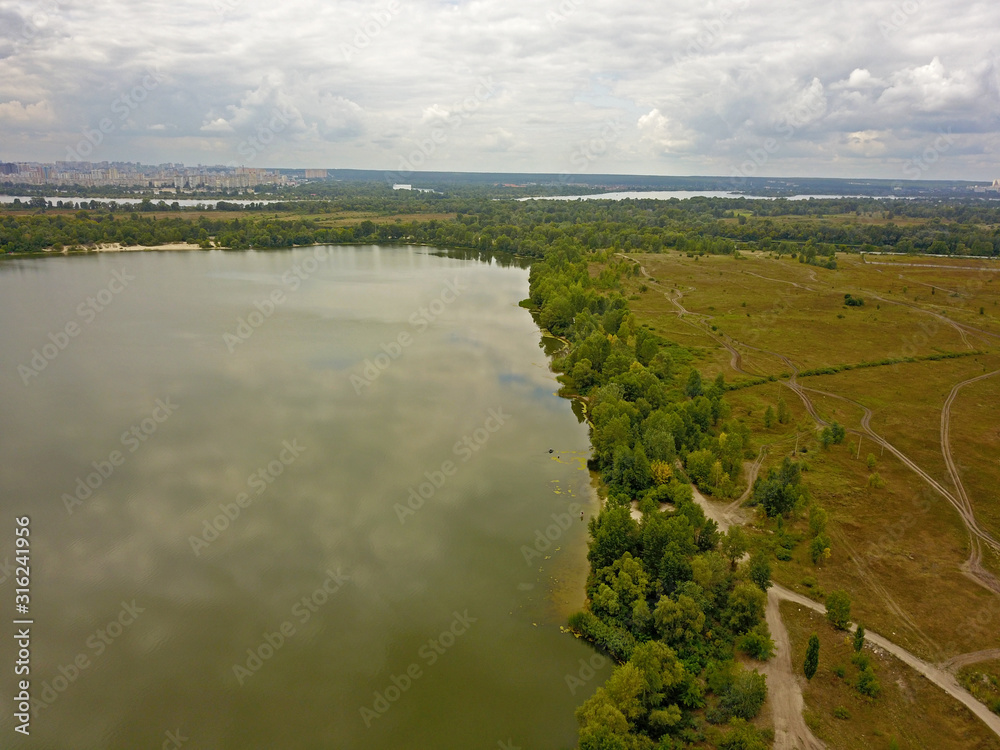 Aeiral drone view. Green banks of the Dnieper River near Kiev in cloudy weather on the outskirts of the city.