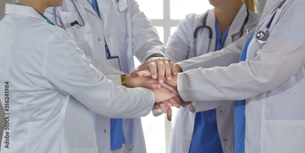 Team of medical workers holding hands together indoors, above view. Unity concept